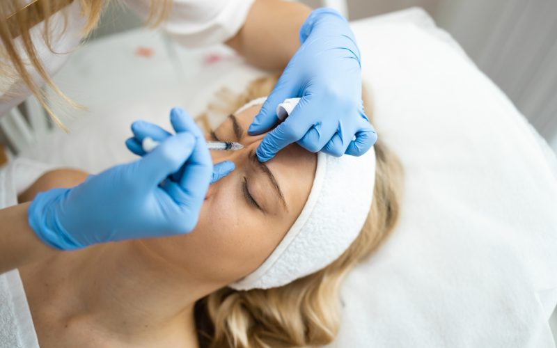 Cosmetologist makes rejuvenating anti wrinkle injections on the face of a beautiful woman.