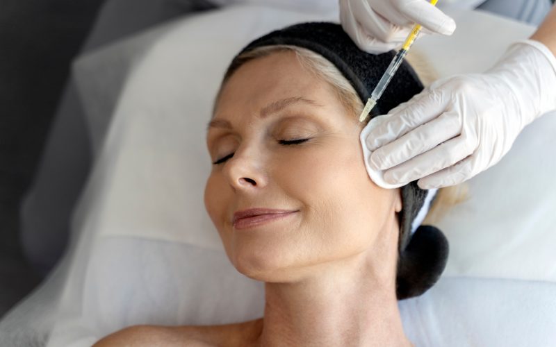 Senior woman relaxing during facial mesotherapy for smoothing of mimic wrinkles